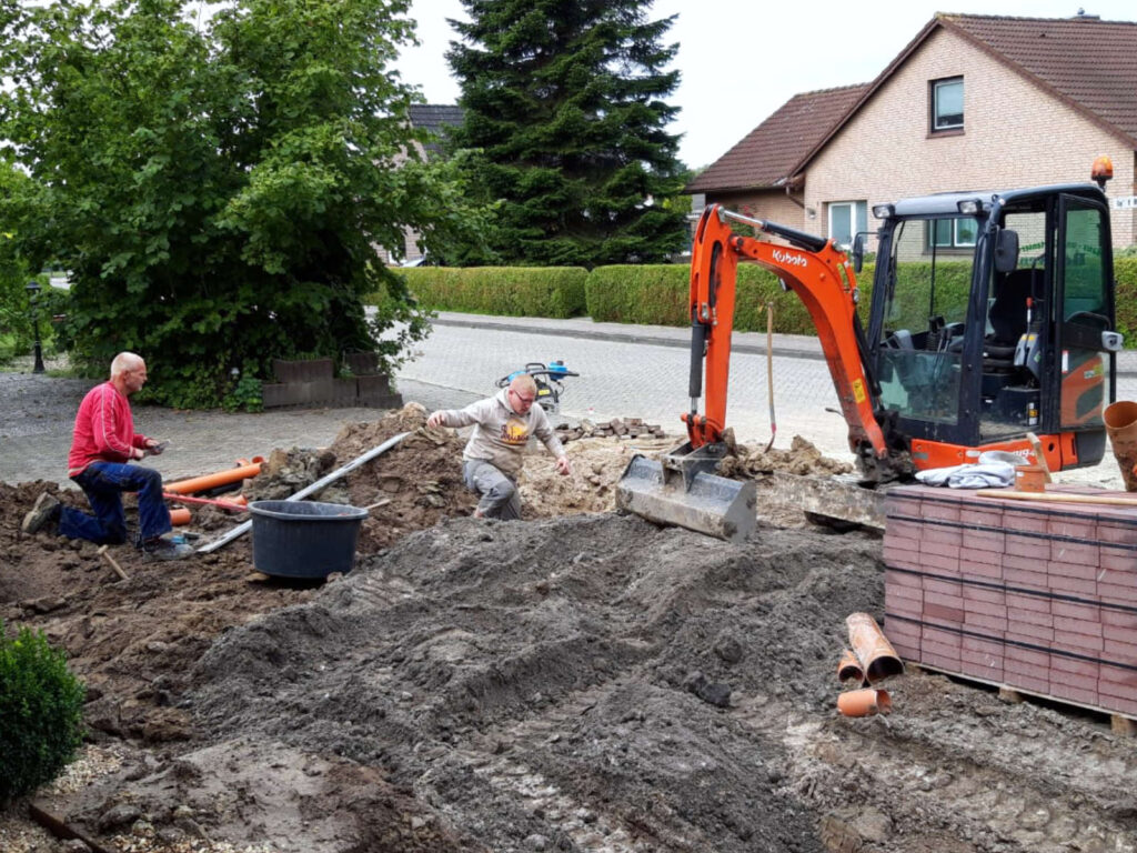 Arbeiter und Minibagger bei Kanalarbeiten