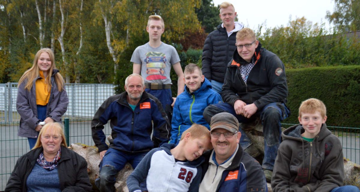 Familie und Teammitglieder von Beewen lächeln auf Baumstamm